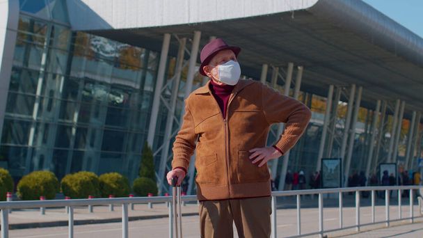 Starszy emeryt dziadek turystyczny noszący maskę ochronną twarzy, uniknąć koronawirusu w pobliżu lotniska - Zdjęcie, obraz