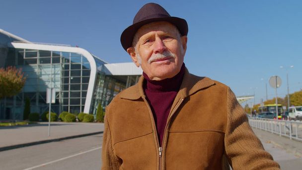 Portrét důchodce turista v blízkosti letištního terminálu čeká na nástup do letadla pro cestování - Fotografie, Obrázek