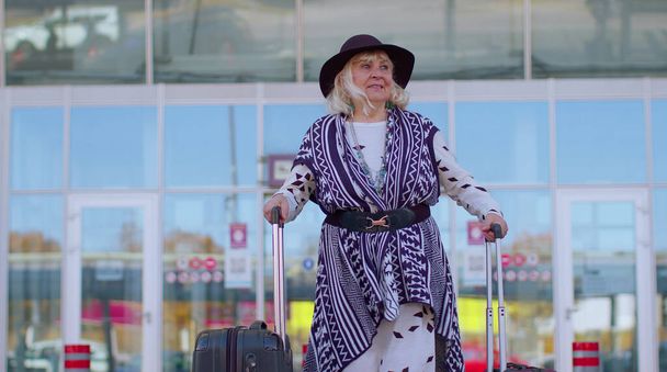Senior důchodce turistické babička obchodní žena chůze od brány letištní haly se zavazadlovou brašnou - Fotografie, Obrázek