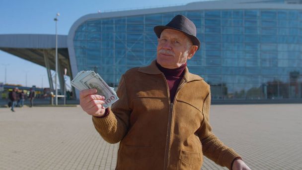 Старший багатий пенсійний бізнес-туристичний дід перебування біля аеропорту тримайте готівку за долари
 - Фото, зображення