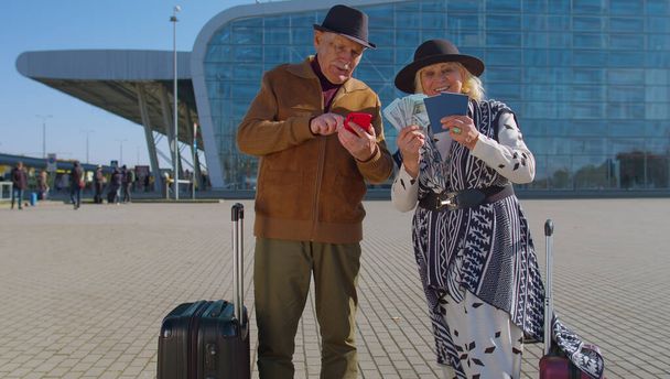 Senior riche retraité touristes grand-mère grand-père rester près de l'aéroport hall détenir de l'argent en argent comptant - Photo, image