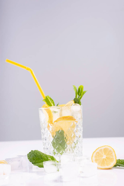 refreshing summer drink in a glass glass with ice, lemon and mint, on a white background. - Valokuva, kuva
