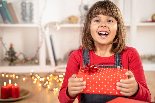 Дівчинка здивована щасливим обличчям і подарунковою коробкою
 - Фото, зображення
