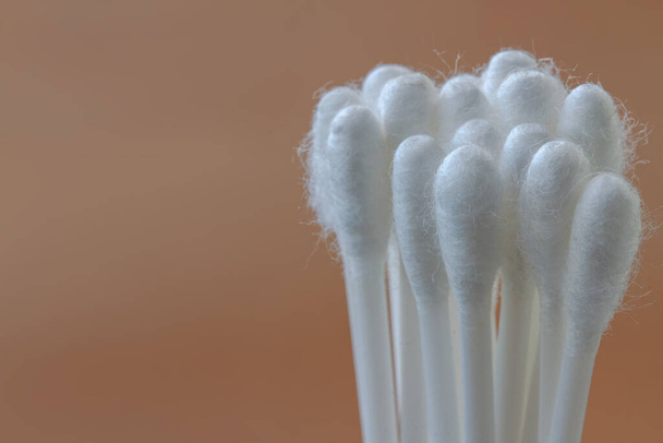 Un groupe de bourgeons de coton blanc avec matière plastique, isolés sur un fond brun, le concept de santé, de beauté et d'hygiène - Photo, image