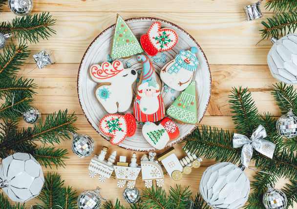 Pan de jengibre de Navidad, galletas en una mesa natural de madera junto a ramas de abeto. Copo de nieve, muñeco de nieve, ciervos, galletas de Papá Noel. Nuevo año maqueta, decoraciones, comida - Foto, Imagen