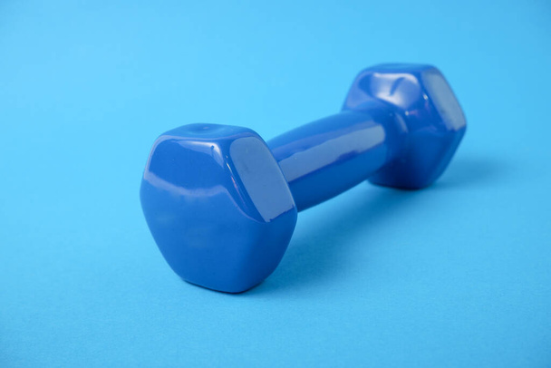Dumbbells in a plastic sheath on a blue background. Training workout equipment. Sport and exercises. - Fotoğraf, Görsel