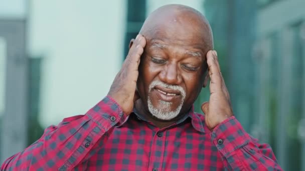 Adult mature person of retirement age frowning unhealthy elderly African American man with gray beard touching massaging temples suffers from migraine feels stressed having headache concept image - Footage, Video