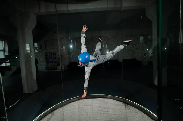 A young woman in overalls and a protective helmet enjoys flying in a wind tunnel. Free fall simulator - Foto, immagini