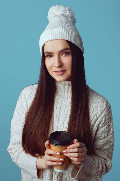 Girl wearing white hat and sweater, enjoys drinking coffee from takeout cup - Photo, image