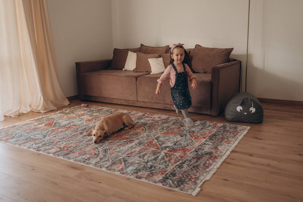 Kleines Mädchen spielt mit Hund in einem gemütlichen schönen Haus  - Foto, Bild