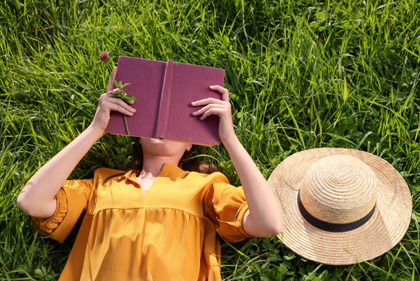 Женщина читает книгу на зеленом лугу, вид сверху - Фото, изображение
