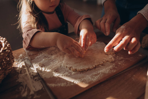 Mother and daughter make cookies from dough in a cozy kitchen  - Zdjęcie, obraz