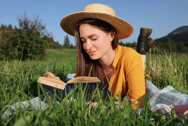 Beautiful young woman reading book on green meadow - Zdjęcie, obraz
