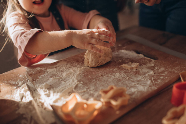 Mother and daughter make cookies from dough in a cozy kitchen  - Foto, afbeelding