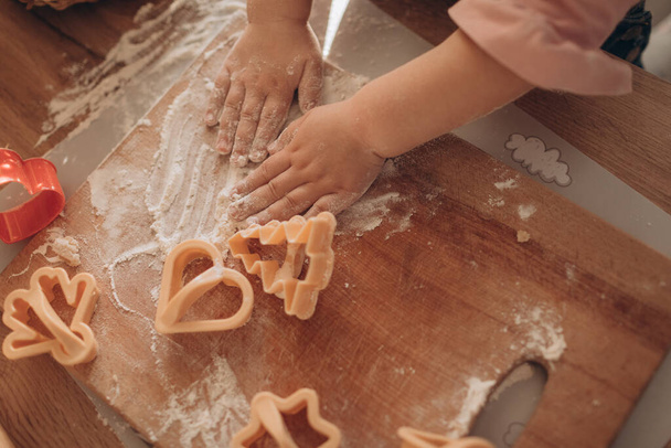 Mother and daughter make cookies from dough in a cozy kitchen  - Fotoğraf, Görsel