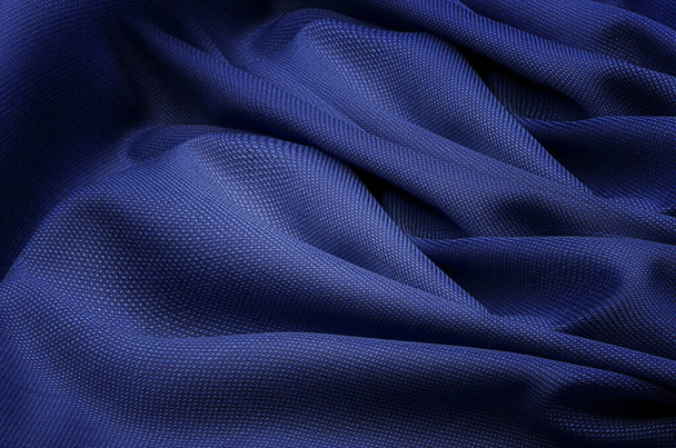 Nahaufnahme Textur aus natürlichem blauem Stoff oder Stoff in derselben Farbe. Gewebestruktur aus natürlicher Baumwolle oder Seide oder Wolle. Blauer Leinwand-Hintergrund. - Foto, Bild