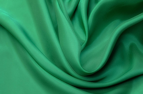 Close-up texture of natural green or emerald fabric or cloth in same color. Fabric texture of natural cotton, silk or wool, or linen textile material. Green canvas background. - Photo, Image