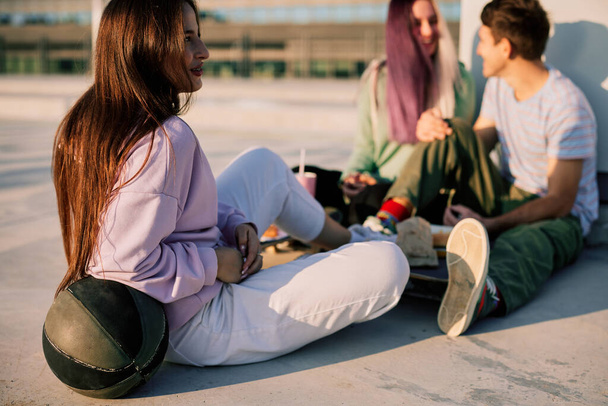 Szczęśliwi nastoletni przyjaciele siedzą na zewnątrz i wiszą po szkole. - Zdjęcie, obraz