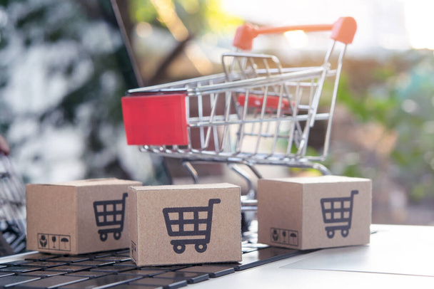 Online vásárlás - Csomag- vagy papírdobozok bevásárlókosár logóval egy kocsi egy laptop billentyűzeten. Bevásárlási szolgáltatás az interneten. házhozszállítás. - Fotó, kép