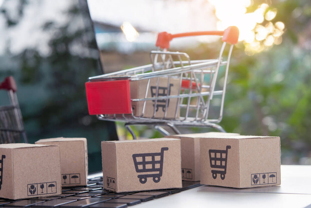 Shopping online - Parcel or Paper cartons with a shopping cart logo in a trolley on a laptop keyboard. Shopping service on The online web. offers home delivery. - Photo, Image