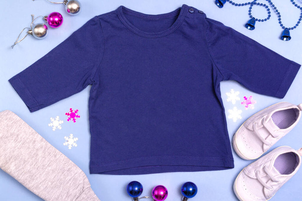 ロゴ、広告の設計と配置のためのモックアップ。ブルーの子供用ラグラン、ポロ、ブラウスのトップビュー、ブルーの背景にモックアップ。赤ちゃんの服の新年フラットロゼット - 写真・画像