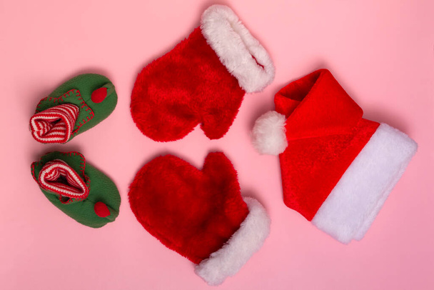 Santa Claus hats, mittens and socks mockup on pink background. Christmas flat mockup, close up top view - Photo, Image