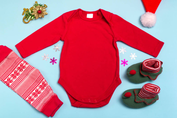 Mockup of New Year's red long sleeve bodysuit on a blue background, decorated with socks, red pants and Christmas tree decorations, top view. Mockup for the design and placement of logos, advertising - Photo, Image