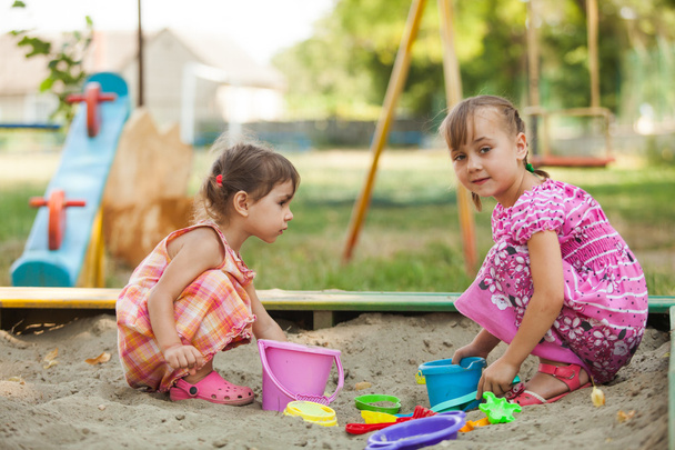 Two girls play in the sandbox - Фото, изображение