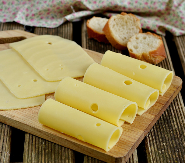 Сырные ломтики на доске и хлеб
 - Фото, изображение