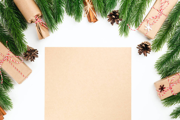 empty craft paper in frame of Christmas pine branches, bundles of cinnamon and cones, festive concert - Фото, изображение