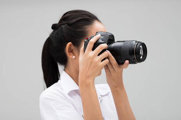 大学生写真家は、被写体を撮影するポイントでカメラを保持し、通常のスーツジャケットを着用します。スタジオ照明グレー背景コピースペース記者ジャーナリスト写真有名人を取る - 写真・画像