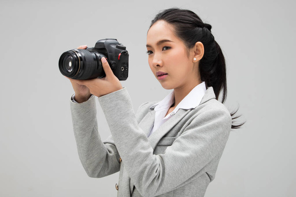 Φοιτητής Φωτογράφος Πανεπιστήμιο κρατήσει φωτογραφική μηχανή με σημείο για να πυροβολήσει το θέμα, φορούν κανονική σακάκι κοστούμι. φωτισμός στούντιο γκρι φόντο αντίγραφο χώρου, δημοσιογράφος λάβει φωτογραφία διασημότητα - Φωτογραφία, εικόνα