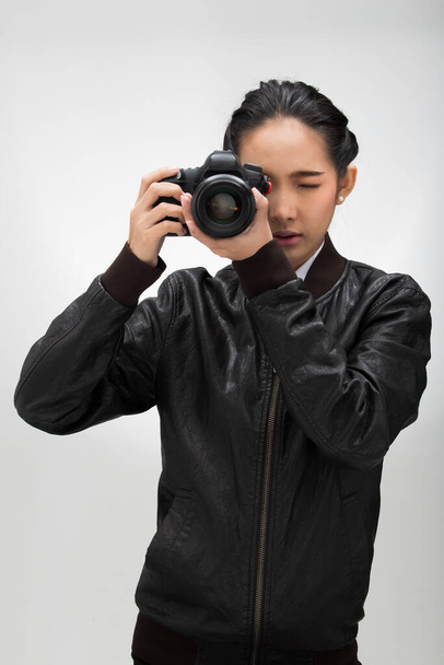 写真家は被写体を撮影するレンズポイントとカメラを保持し、通常のダークブラックのレザースーツジャケットを着用してください。スタジオ照明白グラデーショングレーの背景隔離された記者ジャーナリスト写真有名人を取る - 写真・画像
