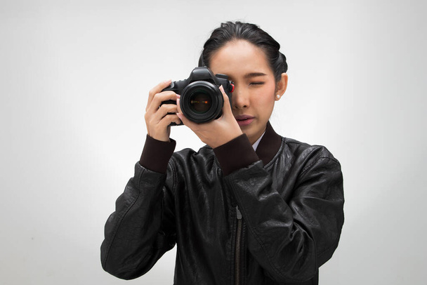 Φωτογράφος κρατήσει φωτογραφική μηχανή με το σημείο φακό για να πυροβολήσει το θέμα, φορούν κανονική σκούρο μαύρο σακάκι leater κοστούμι. στούντιο φωτισμού λευκό κλίση γκρι φόντο απομονωμένο, δημοσιογράφος λάβει φωτογραφία διασημότητα - Φωτογραφία, εικόνα