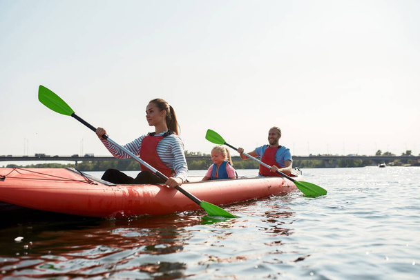 Young european family floats on kayak in lake - Foto, imagen