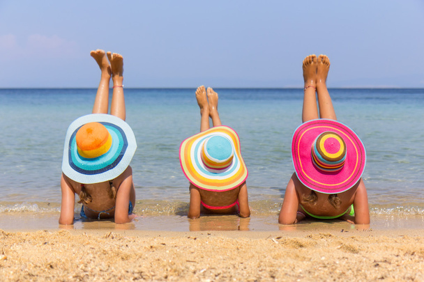 Дівчата з барвистим капелюхом на пляжі
 - Фото, зображення