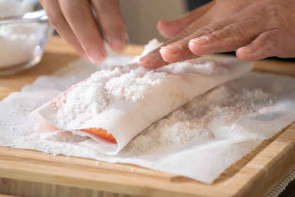 Saumon mariné au sel sur papier mousseline qualité alimentaire sur plaque de découpe en bois par le chef professionnel. - Photo, image