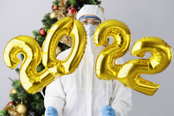 Lääkäri suojapuku, naamio ja lasit omistaa numerot 2022 taustaa vasten uudenvuoden puu - Valokuva, kuva