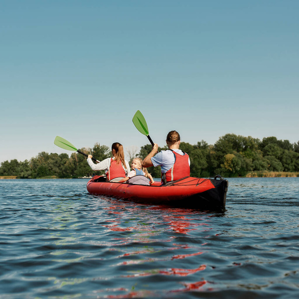 Young caucasian family floats on kayak in lake - Foto, Imagen