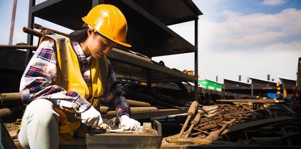 Asiática mujer trabajadora de mantenimiento con un casco y chaleco amarillo está sosteniendo una llave inglesa trabajando en almacén. - Foto, imagen