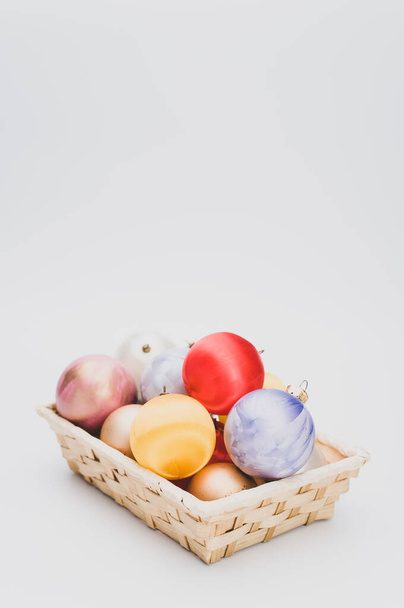 Multicolored Christmas decorative balls in a wicker canister with sapce for text - Foto, afbeelding