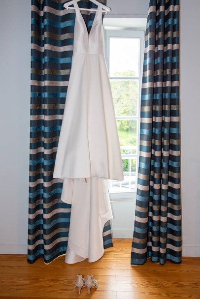 Robe de mariée robe blanche dans la maison pour une mariée pendaison fenêtres chambre - Photo, image