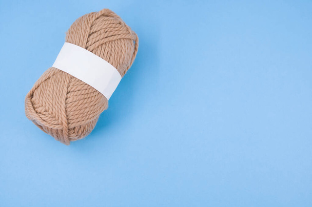A vertical shot of isolated beige yarn on blue background with text space - Photo, Image