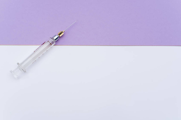 an isolated injection syringe on mauve paper background with text space - Foto, Imagem