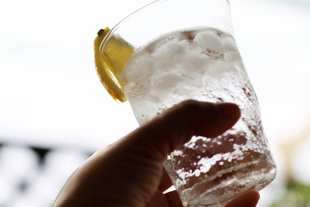 Weibliche Hand hält ein Glas mit Whiskey-Limonade - Foto, Bild