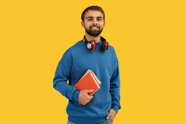 Student with headphones and books on yellow background - Foto, Imagem