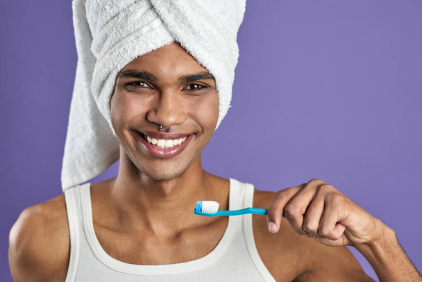 Retrato en la cabeza del joven con cepillo de dientes en la mano aislado sobre fondo púrpura - Foto, Imagen