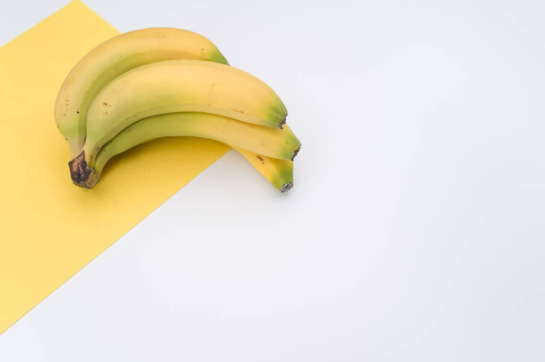 ripe biologic bananas on a white and yellow background with copy space - 写真・画像