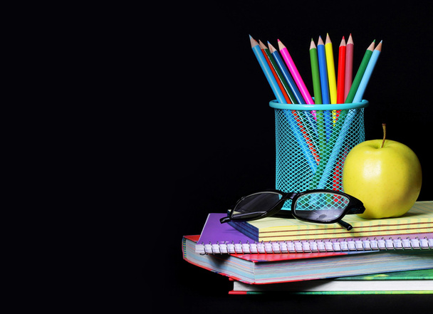 Forniture scolastiche sul nero. Una mela, matite colorate
 - Foto, immagini