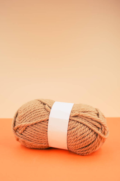 A vertical shot of isolated beige yarn on orange background with text space - Foto, immagini